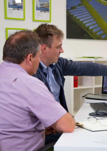 Zwei Männer sitzen am Schreibtisch und beraten sich