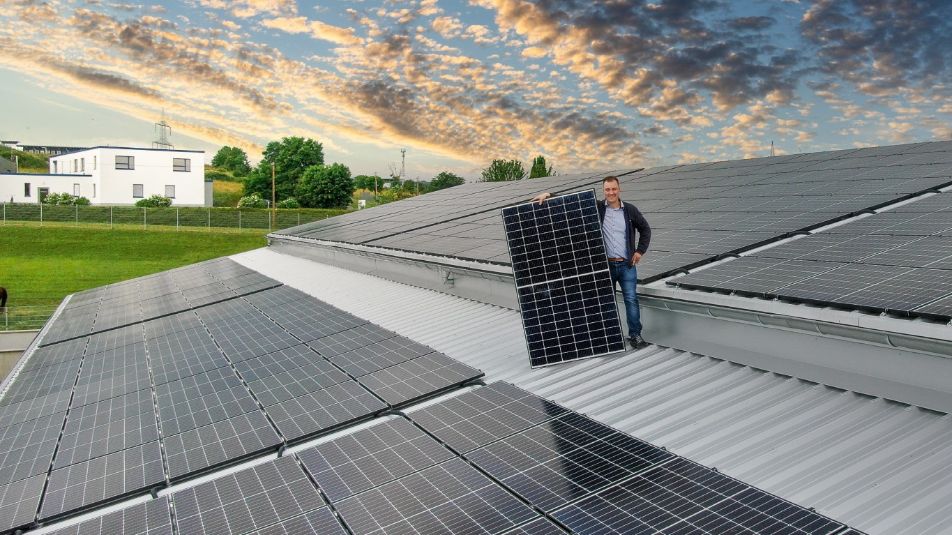 Ein Mann steht auf einem Dach mit Solarmodulen